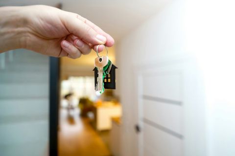 A hand holding house keys in front of a front door