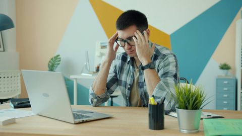 A business owner overwhelmed at a desk covered in work